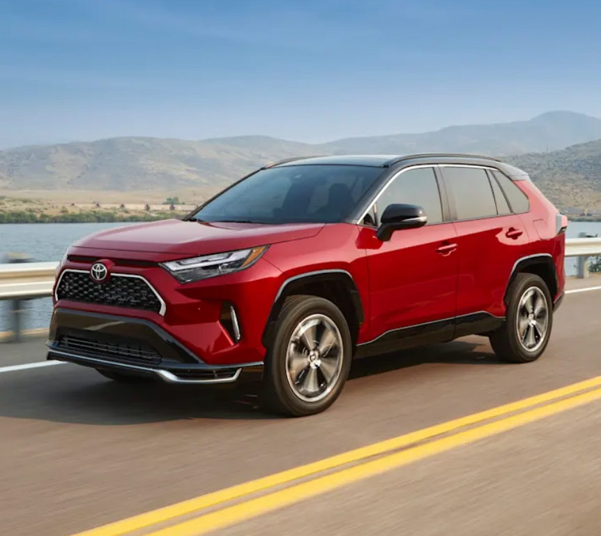 2025 TOYOTA RAV4 PLUG-IN RED DRIVING DOWN ROAD